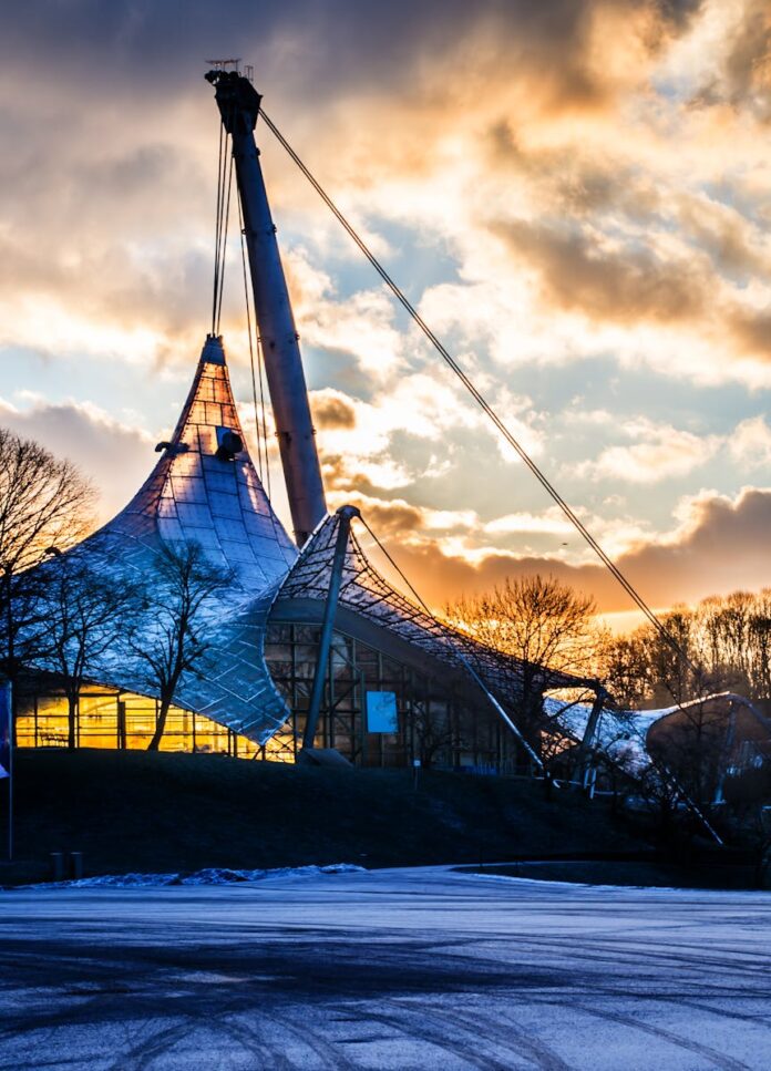 The iconic Olympiapark structure in Munich captured at dusk with vibrant clouds.